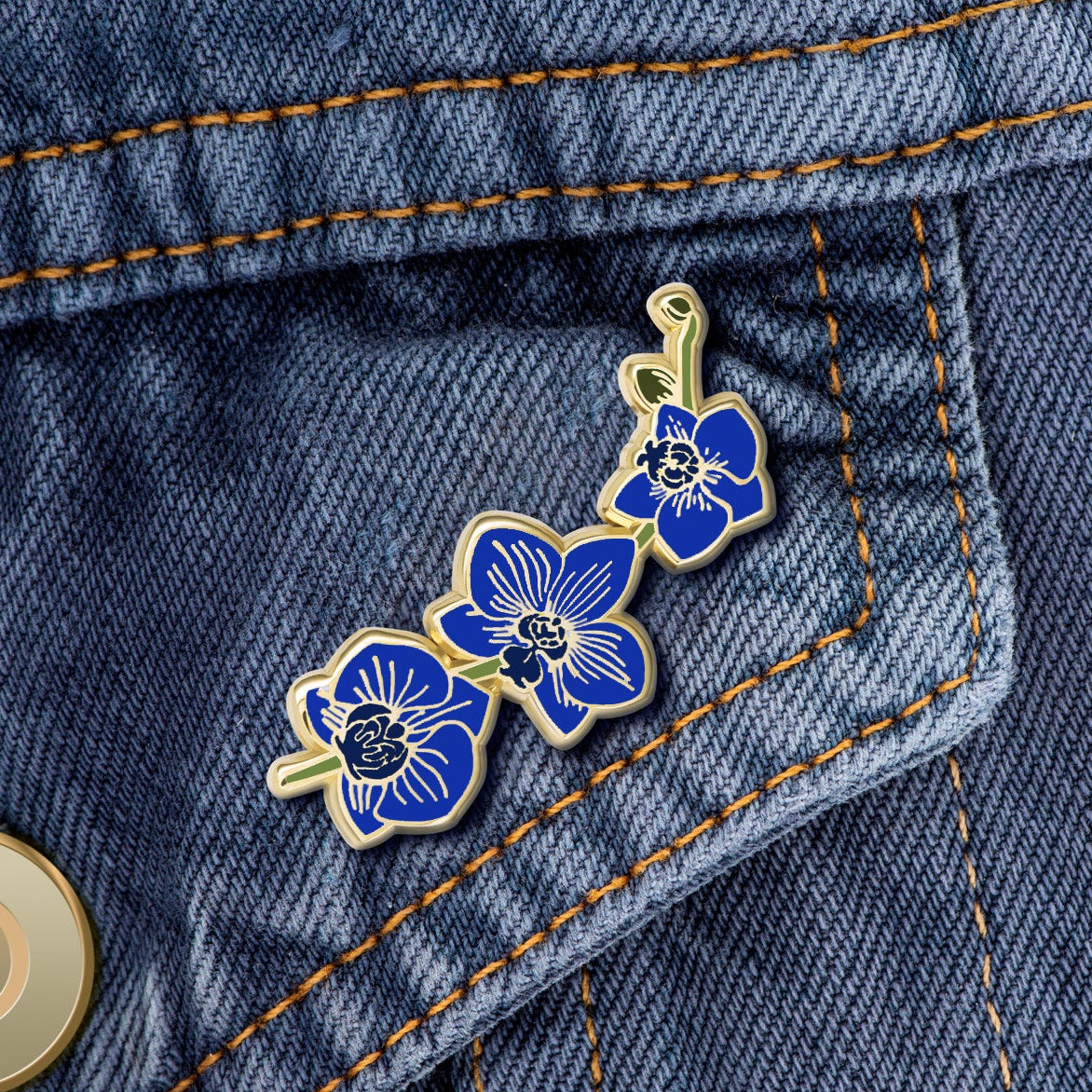 Blue orchid enamel pin on denim jacket pocket