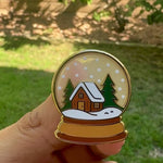 Load and play video in Gallery viewer, Snow Globe Enamel Pin with Cozy Cabin | Winter Holiday Lapel Pin | Christmas Snowy Cottage Badge | Cute Stocking Stuffer Gift
